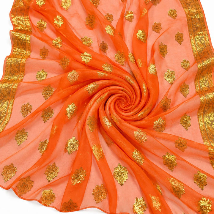 Orange lurex chiffon med gyldne motiver og guldborter – stoffet formet som en spiral (billede 1 af 3)