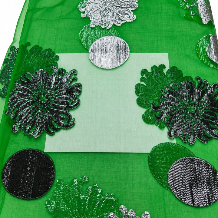 Smaragdgrøn lurex chiffonsilk – nærbillede af blomster- og cirkelmotiverne og stoffets gennemsigtighed (billede 3 af 3)