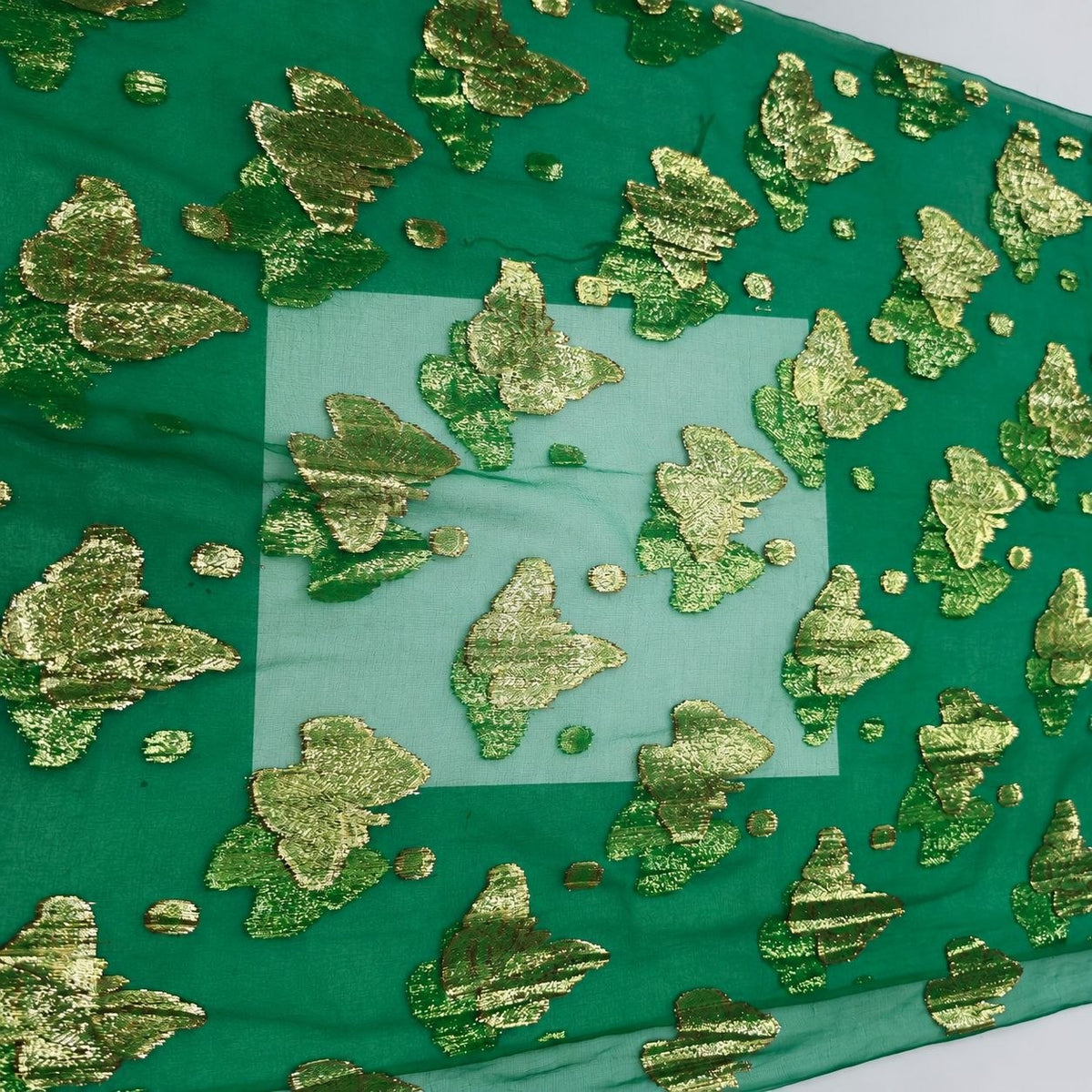 Smaragdgrøn lurex chiffonsilk – nærbillede af sommerfuglemotiverne, prikkerne og stoffets gennemsigtighed (billede 3 af 3)