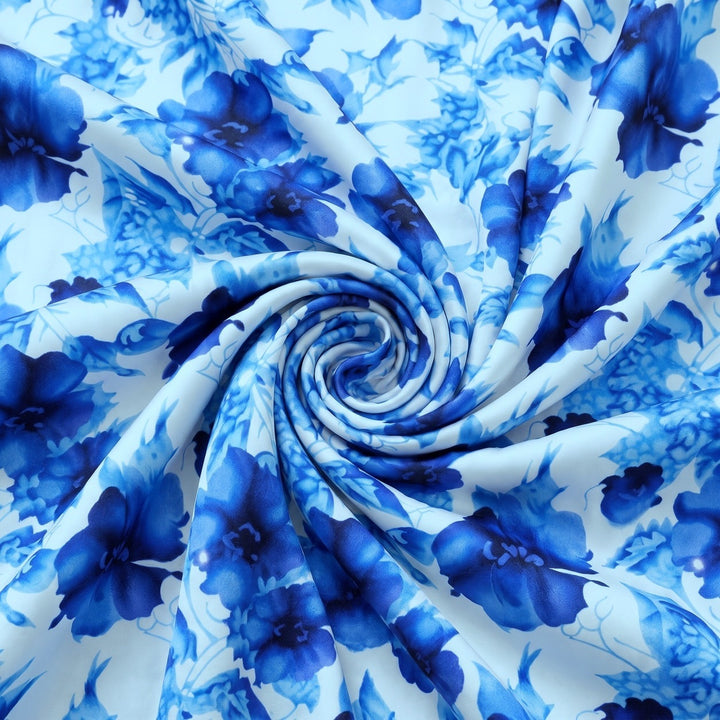 BLOMSTRET POLYESTERSTOF – BLÅ/HVID – stoffet samlet i en blød swirl, med printet synligt (billede 1 af 3)