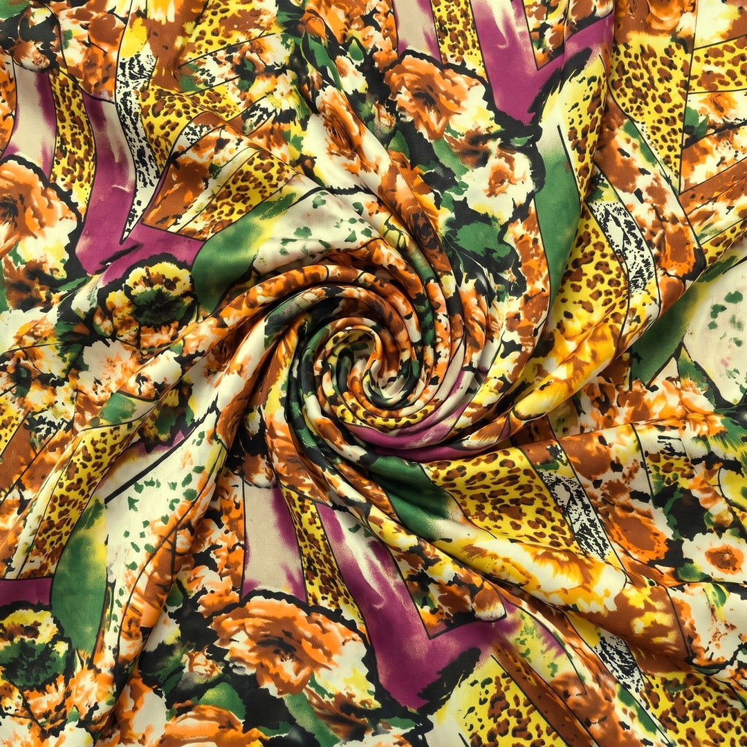 MØNSTRET POLYESTERSTOF – GUL/ORANGE/LILLA MULTI – stoffet samlet i en blød swirl, med printet synligt (billede 1 af 3)