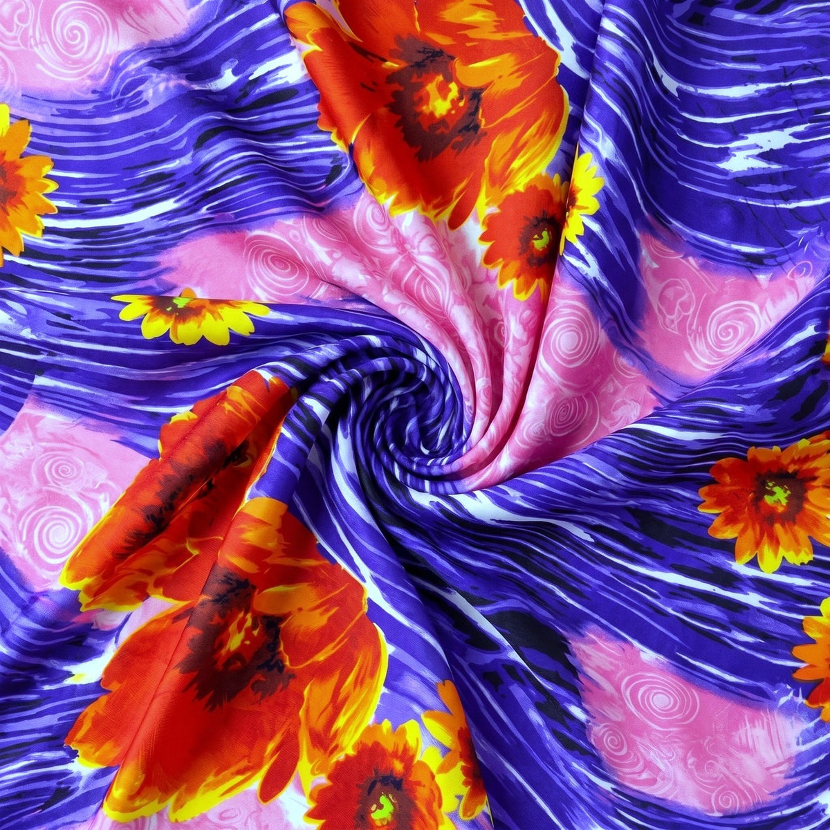 MØNSTRET POLYESTERSTOF – LILLA/PINK/ORANGE – stoffet samlet i en blød swirl, med printet synligt (billede 1 af 3)