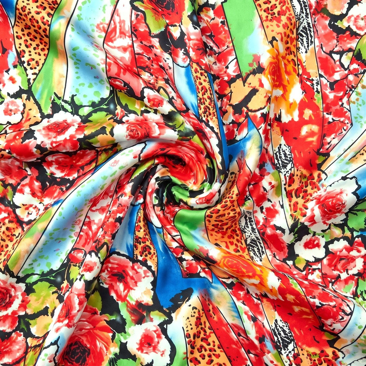 MØNSTRET POLYESTERSTOF – RØD/PINK/ORANGE MULTI – stoffet samlet i en blød swirl, med printet synligt (billede 1 af 3)