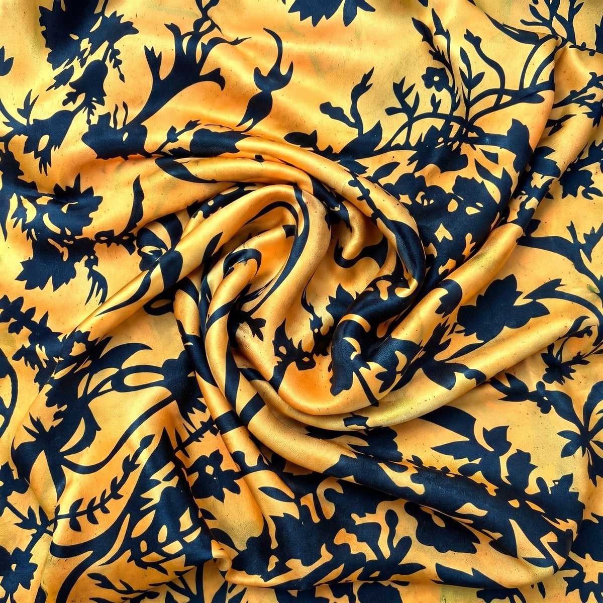 Orange og guld silke med mørkeblåt blomsterprint – hele mønstret – stoffet samlet i en blød swirl, med printet synligt (billede 1 af 3)