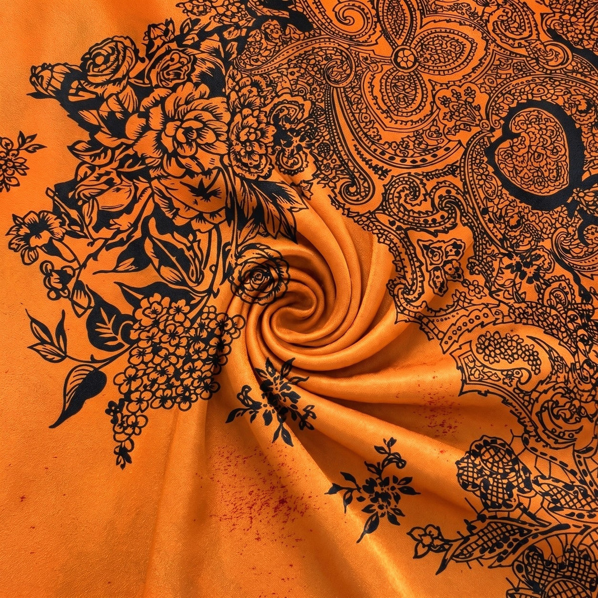 Orange silke med paisleyprint – hele mønstret med pletter synlige – stoffet samlet i en blød swirl, med printet synligt (billede 1 af 4)