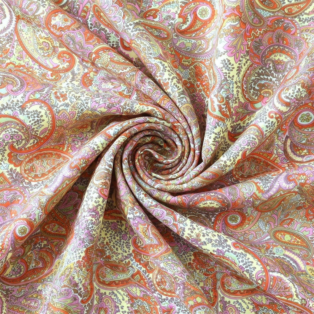 PAISLEY POLYESTERSTOF – CREME/KORAL/MULTI – stoffet samlet i en blød swirl, med printet synligt (billede 1 af 3)