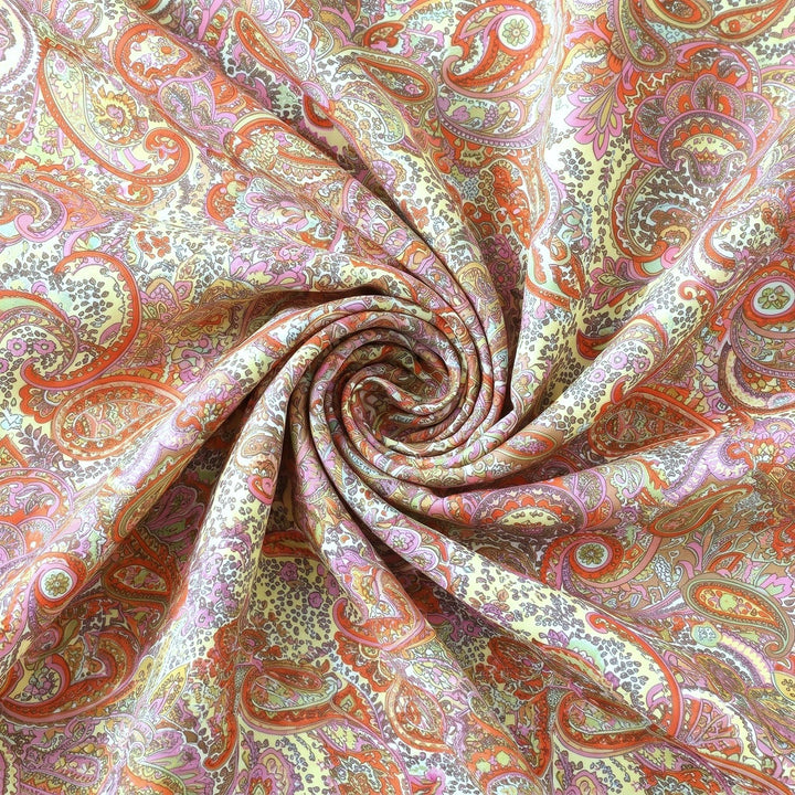 PAISLEY POLYESTERSTOF – CREME/KORAL/MULTI – stoffet samlet i en blød swirl, med printet synligt (billede 1 af 3)