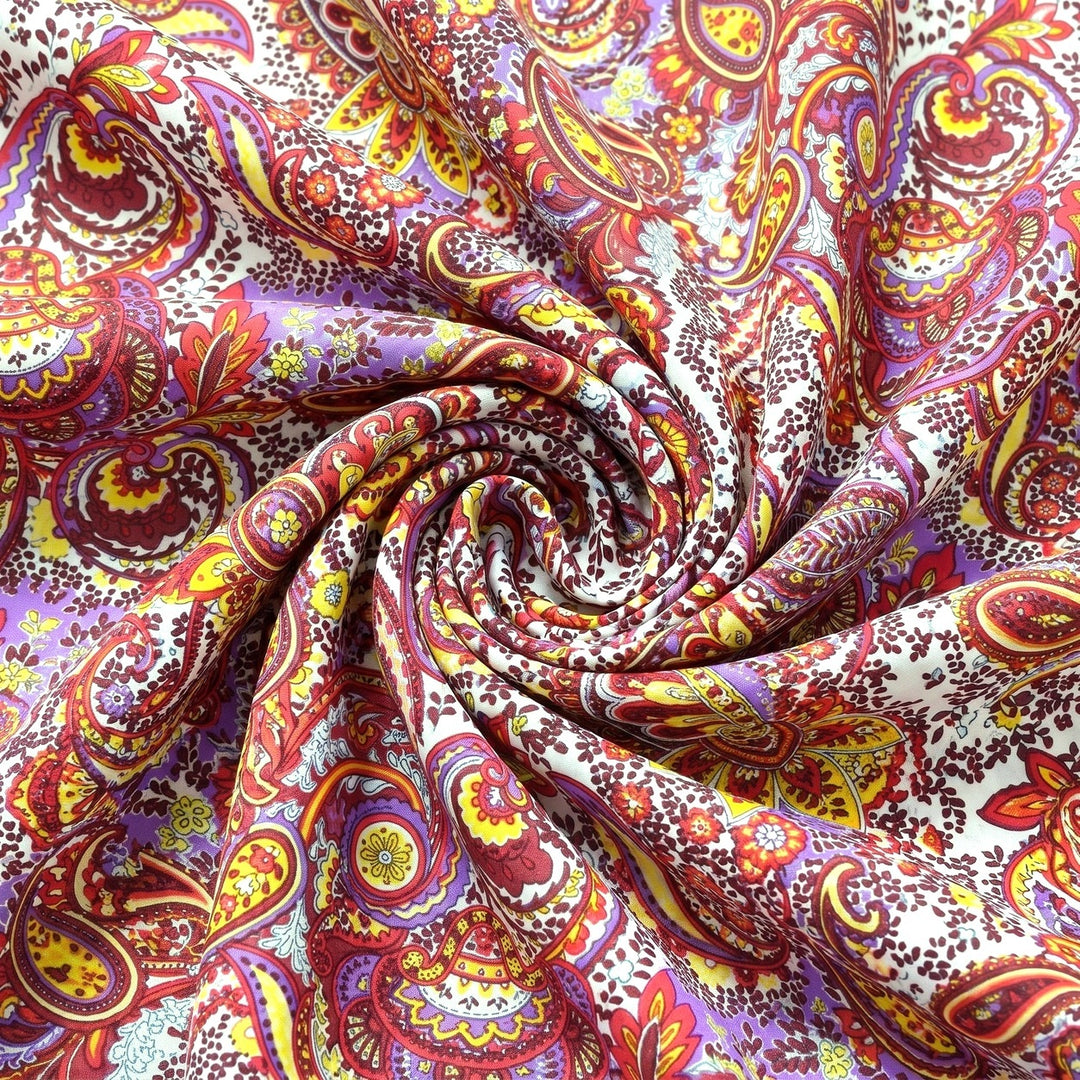 PAISLEY POLYESTERSTOF – LILLA/GUL/RØD MULTI – stoffet samlet i en blød swirl, med printet synligt (billede 1 af 3)