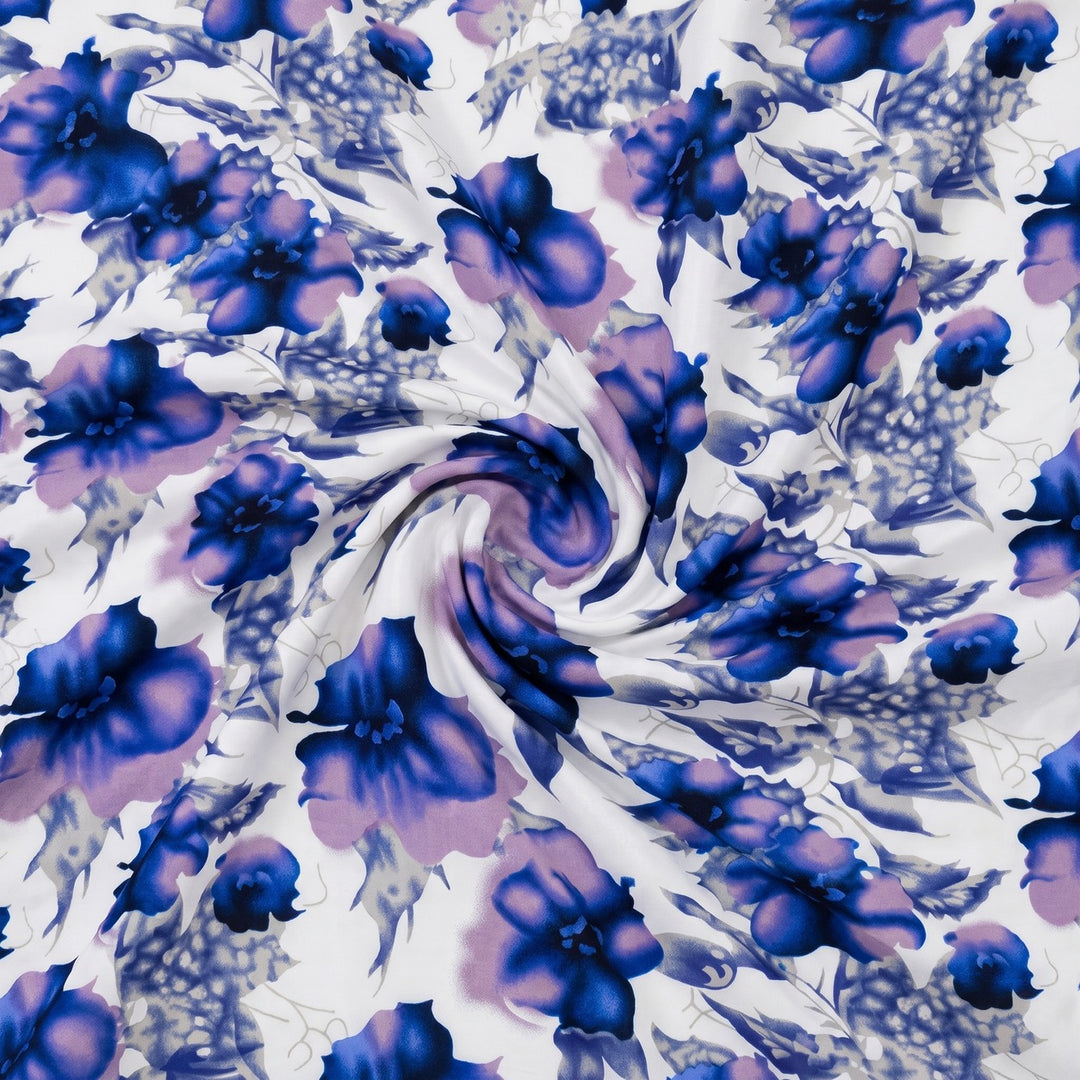 POLYESTERSTOF MED BLOMSTER – BLÅ/HVID – stoffet samlet i en blød swirl, med blomsterprintet synligt (billede 1 af 3)