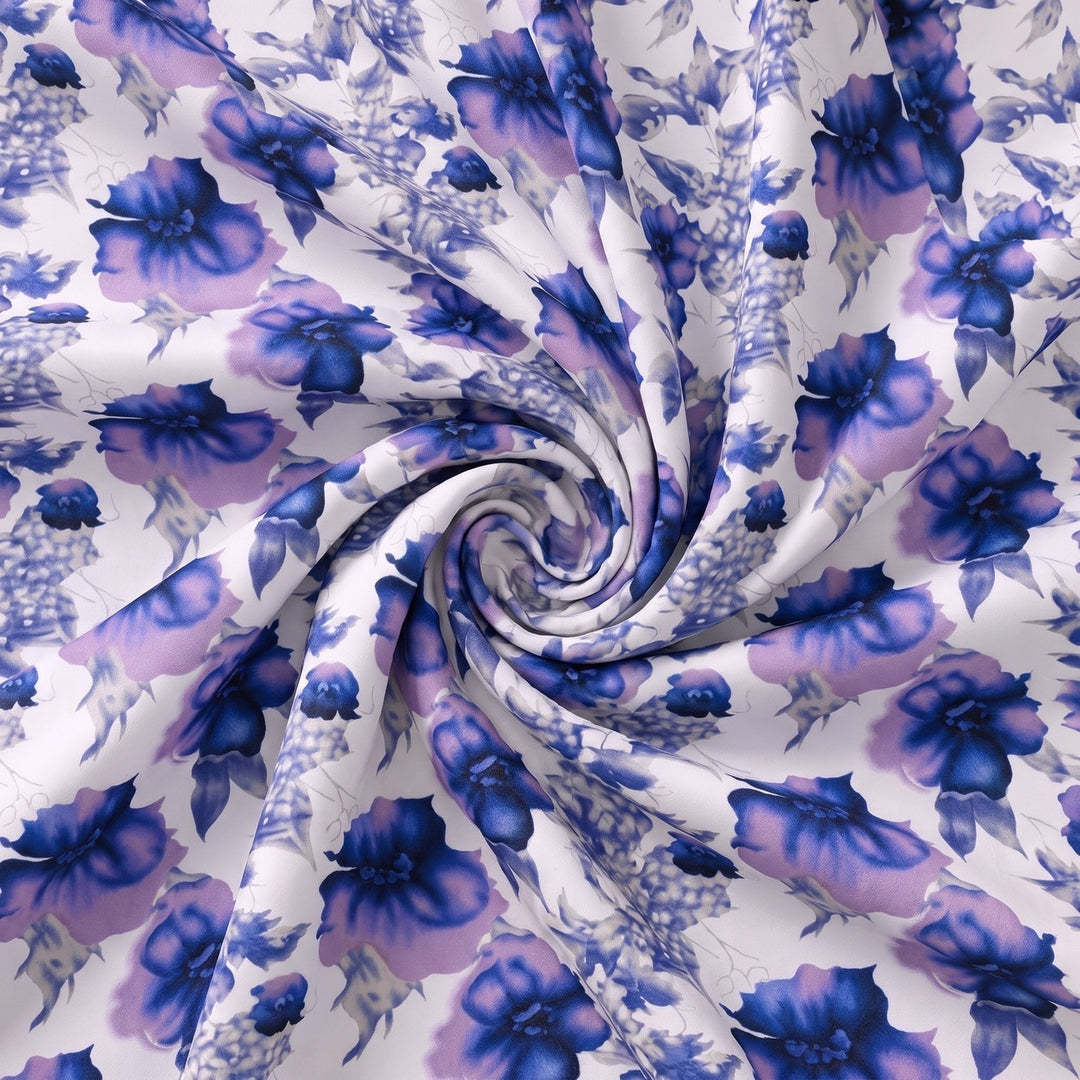 POLYESTERSTOF MED BLOMSTER – BLÅ/HVID – stoffet samlet i en blød swirl, med blomsterprintet synligt – stoffet samlet i en blød swirl, med printet synligt (billede 1 af 3)