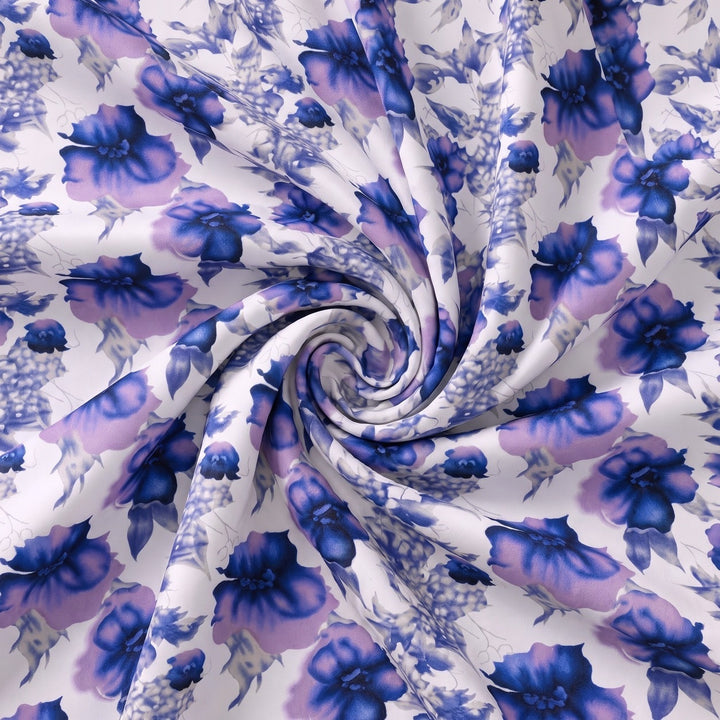 POLYESTERSTOF MED BLOMSTER – BLÅ/HVID – stoffet samlet i en blød swirl, med blomsterprintet synligt – stoffet samlet i en blød swirl, med printet synligt (billede 1 af 3)