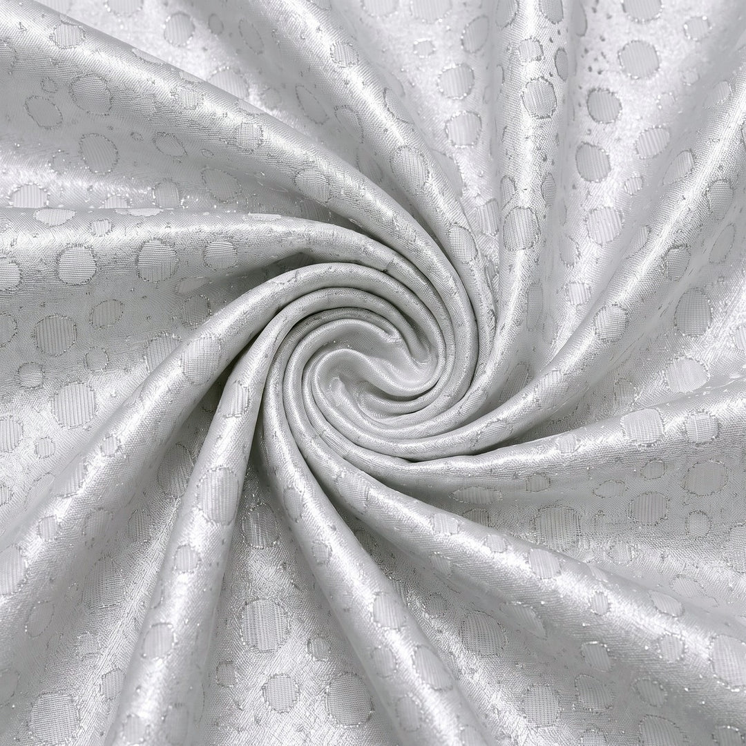 SØLV SATIN JACQUARD STOF MED PRIKKER – stoffet samlet i en blød swirl, med det vævede prikmønster synligt (billede 1 af 3)
