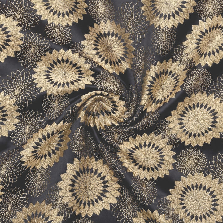 MØRKEBLÅ SATIN JACQUARD STOF MED GULD BLOMSTER – stoffet samlet i en blød swirl, med det vævede mønster synligt (billede 1 af 3)